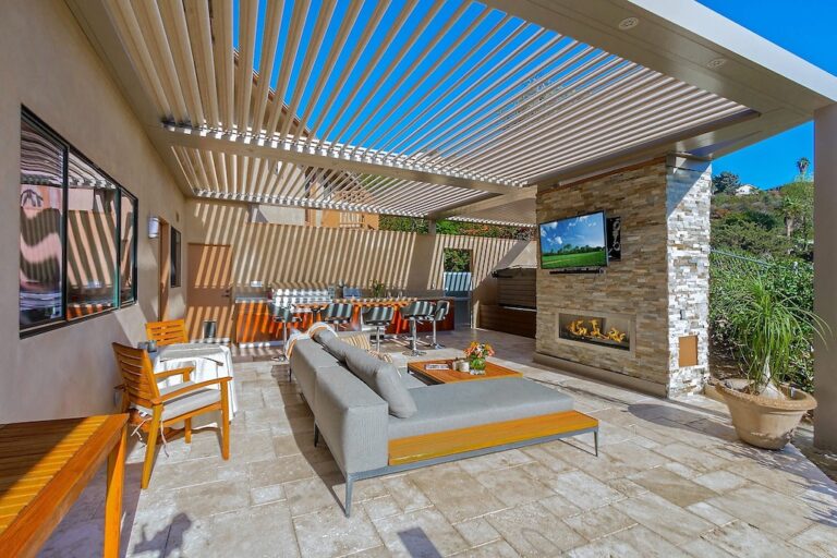 outdoor patio with sitting space and television covered by a pergola