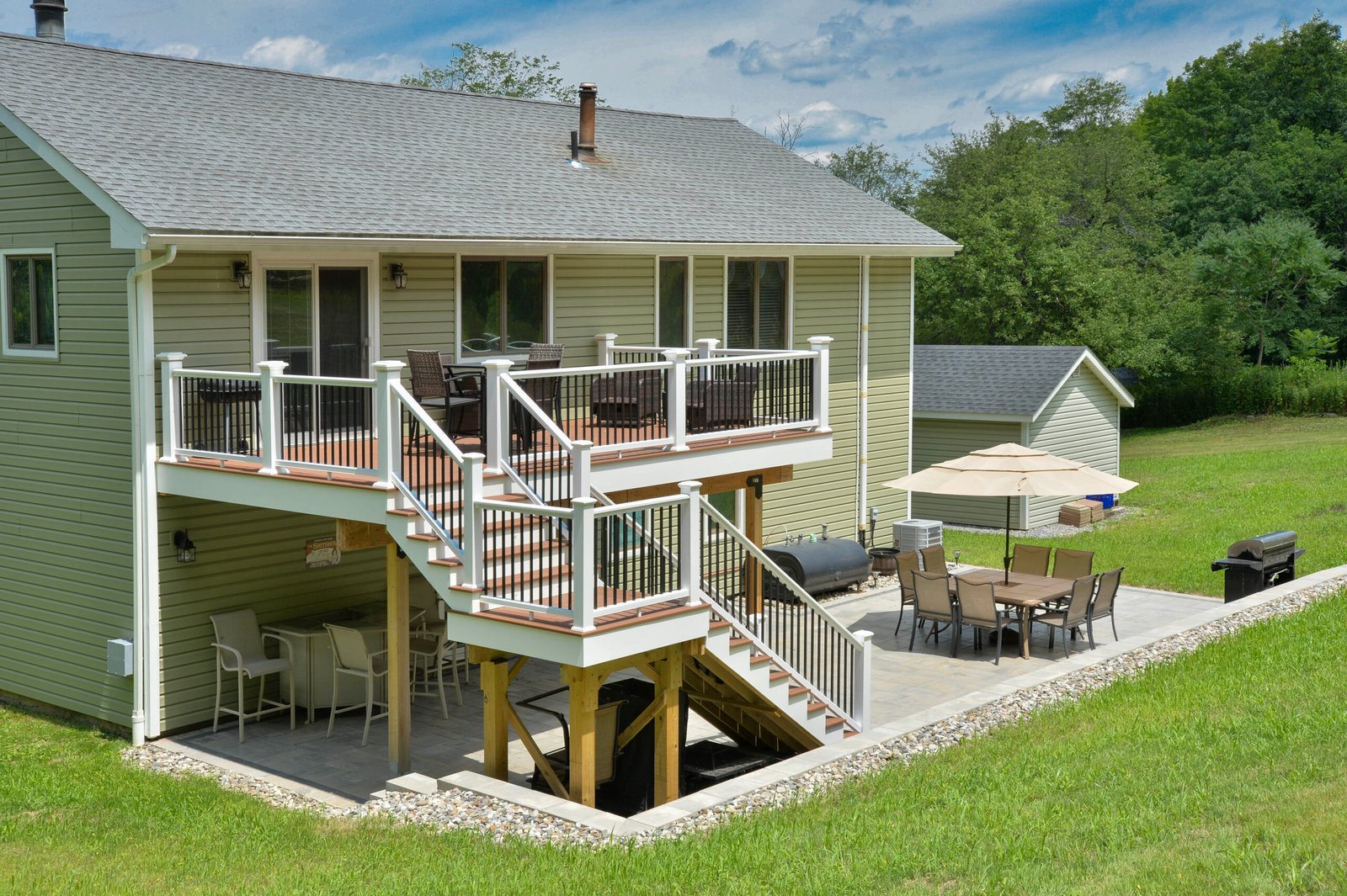 Aerial view of a two story deck with a paved patio including an outdoor seating area