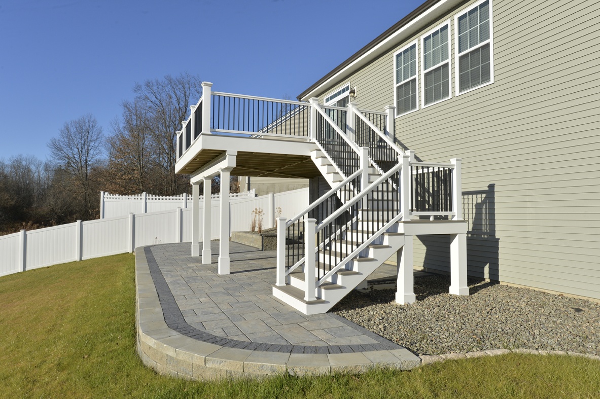 view of 2-story backyard deck with stone hardscaping in sloping backyard