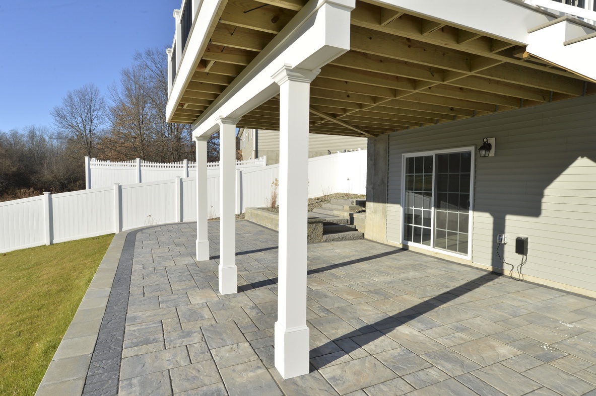 white columns on stone hardscape supporting 2-story backyard deck