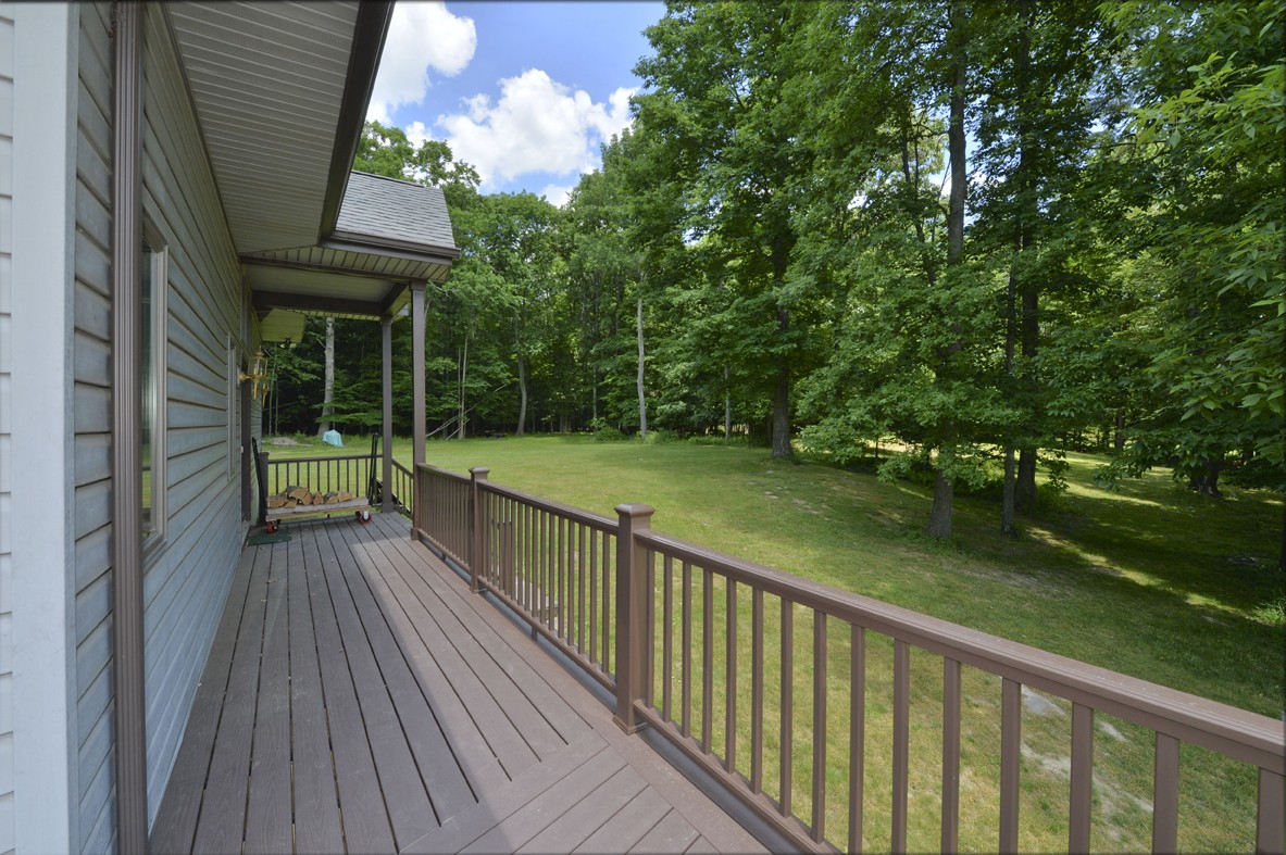 beautiful side view of custom brown deck and secluded wooded backyard