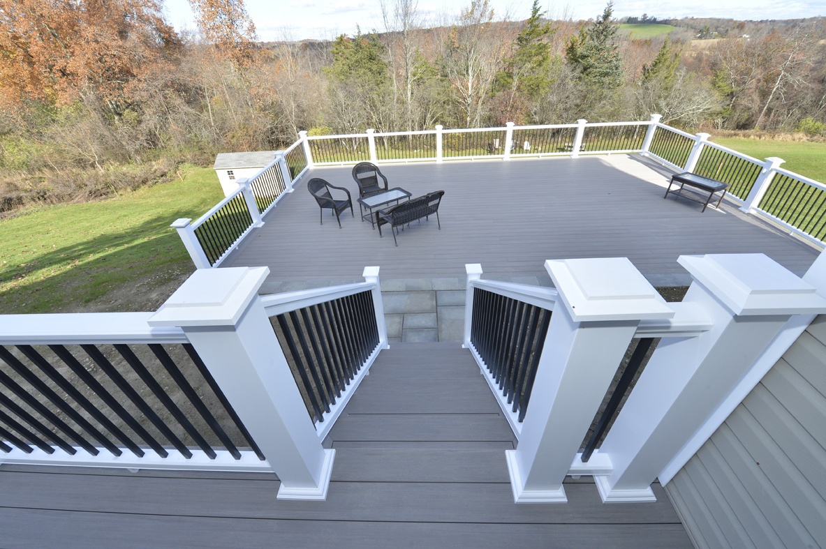 view from top of stairs looking down to hillside deck with white railing overlooking tree grove