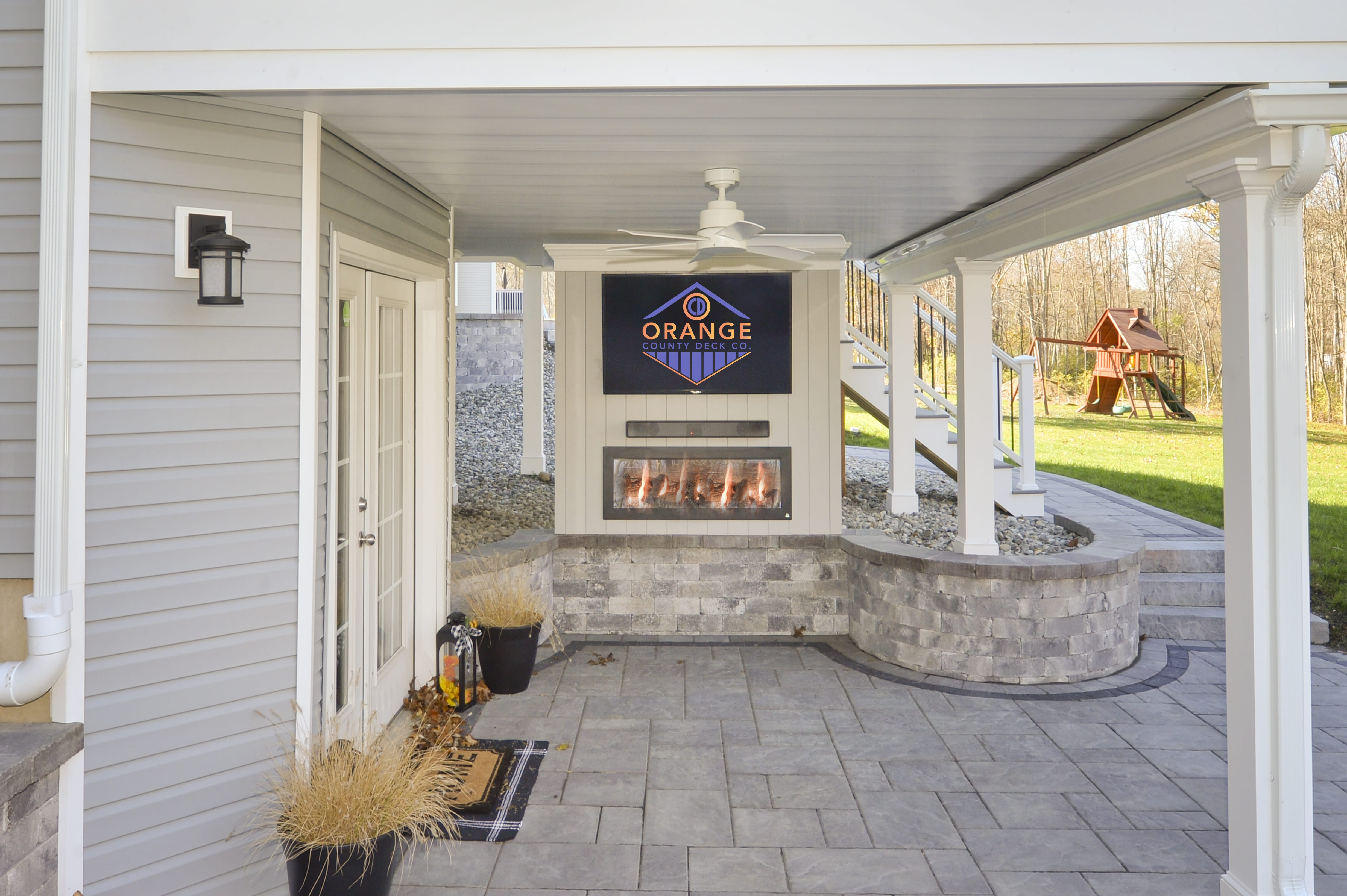 lower story with hardscaping for custom deck with ocdeckco logo on outdoor tv